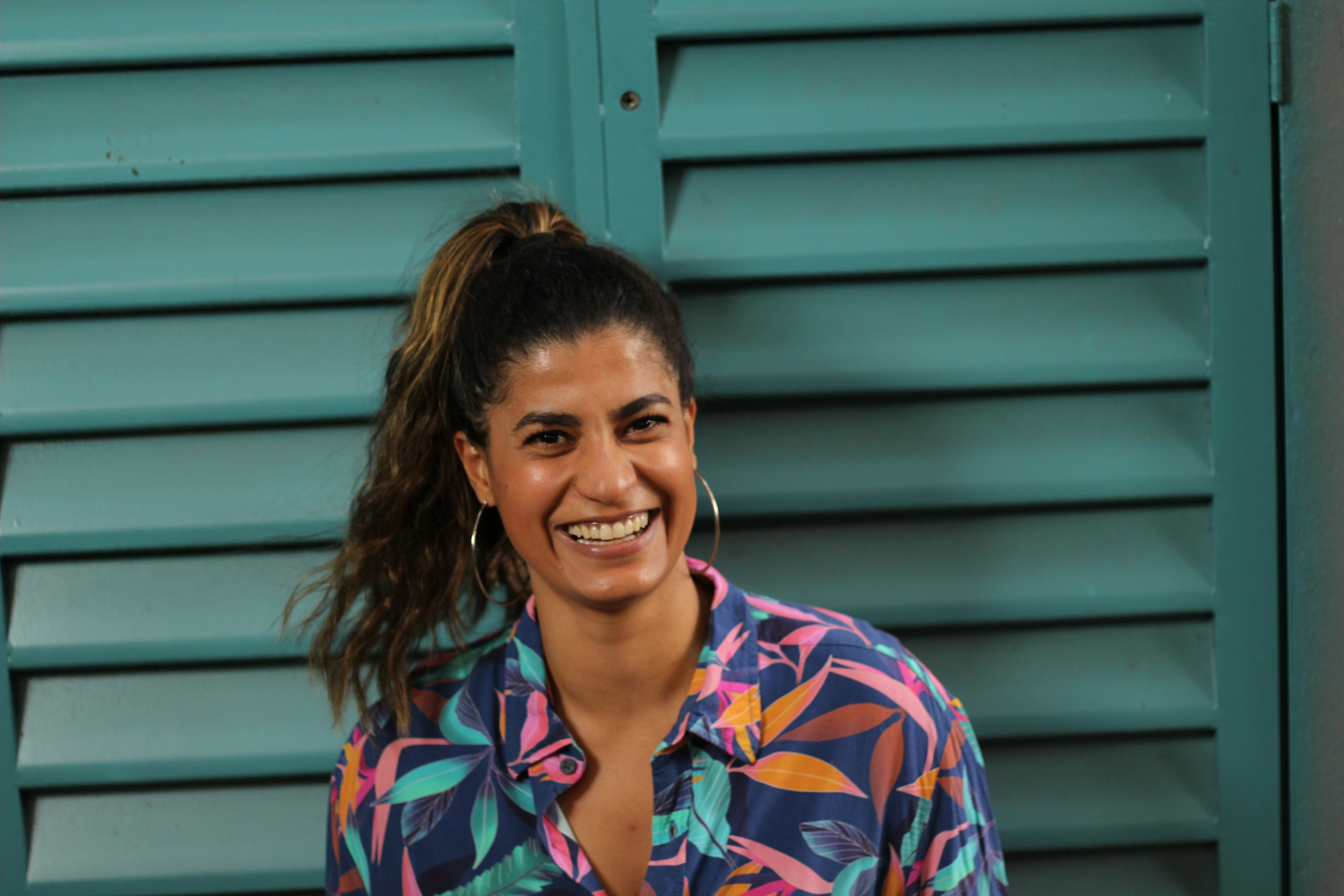 Mujer sonriente con camisa a cuadros azul, roja y blanca abotonada