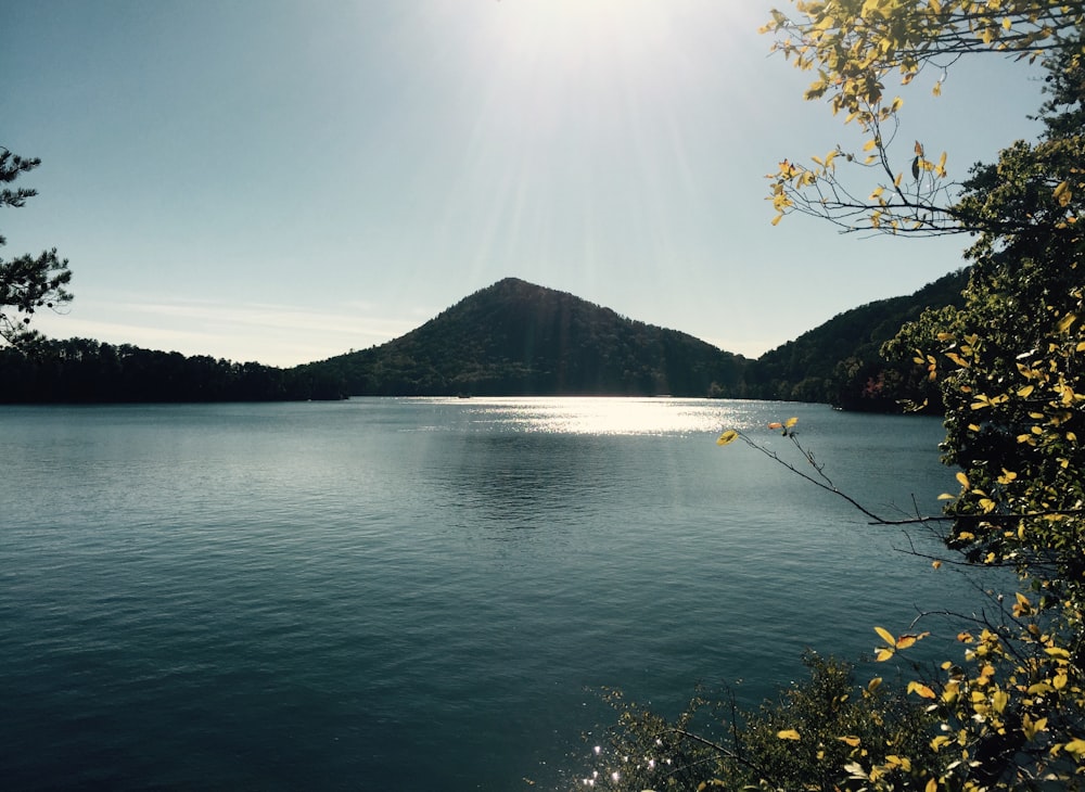 body of water near mountain during daytime