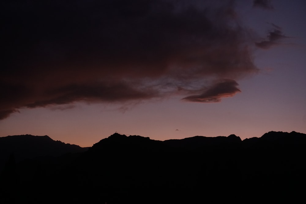 silhouette of mountain under cloudy sky during daytime