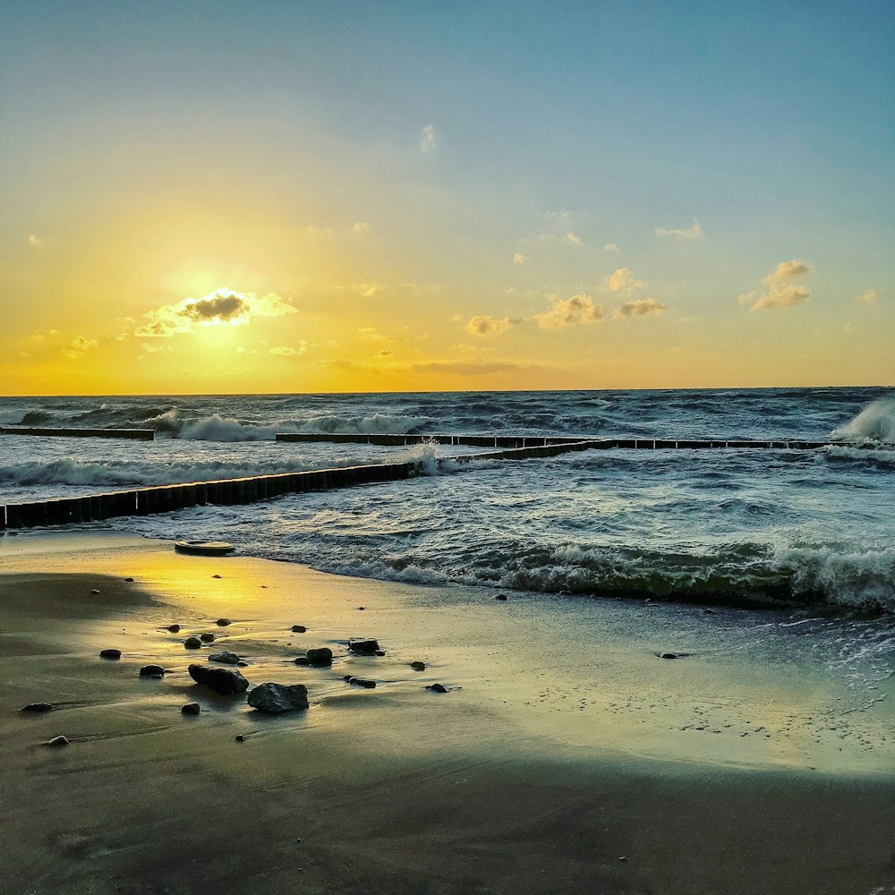 sea waves crashing on shore during sunset