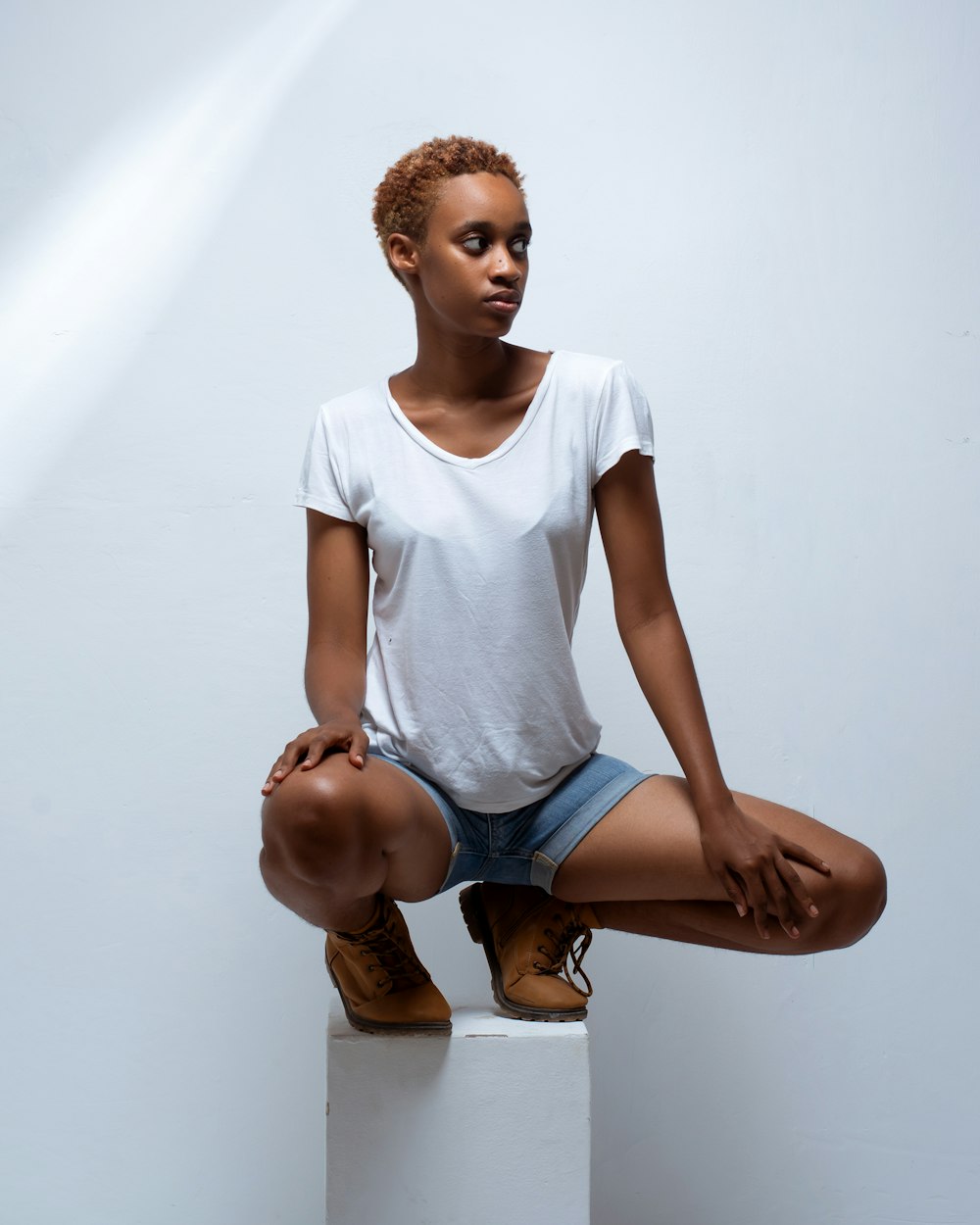 girl in white crew neck t-shirt and blue denim shorts sitting on floor