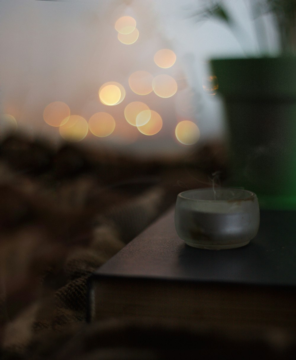 white candle in clear glass holder on brown wooden table