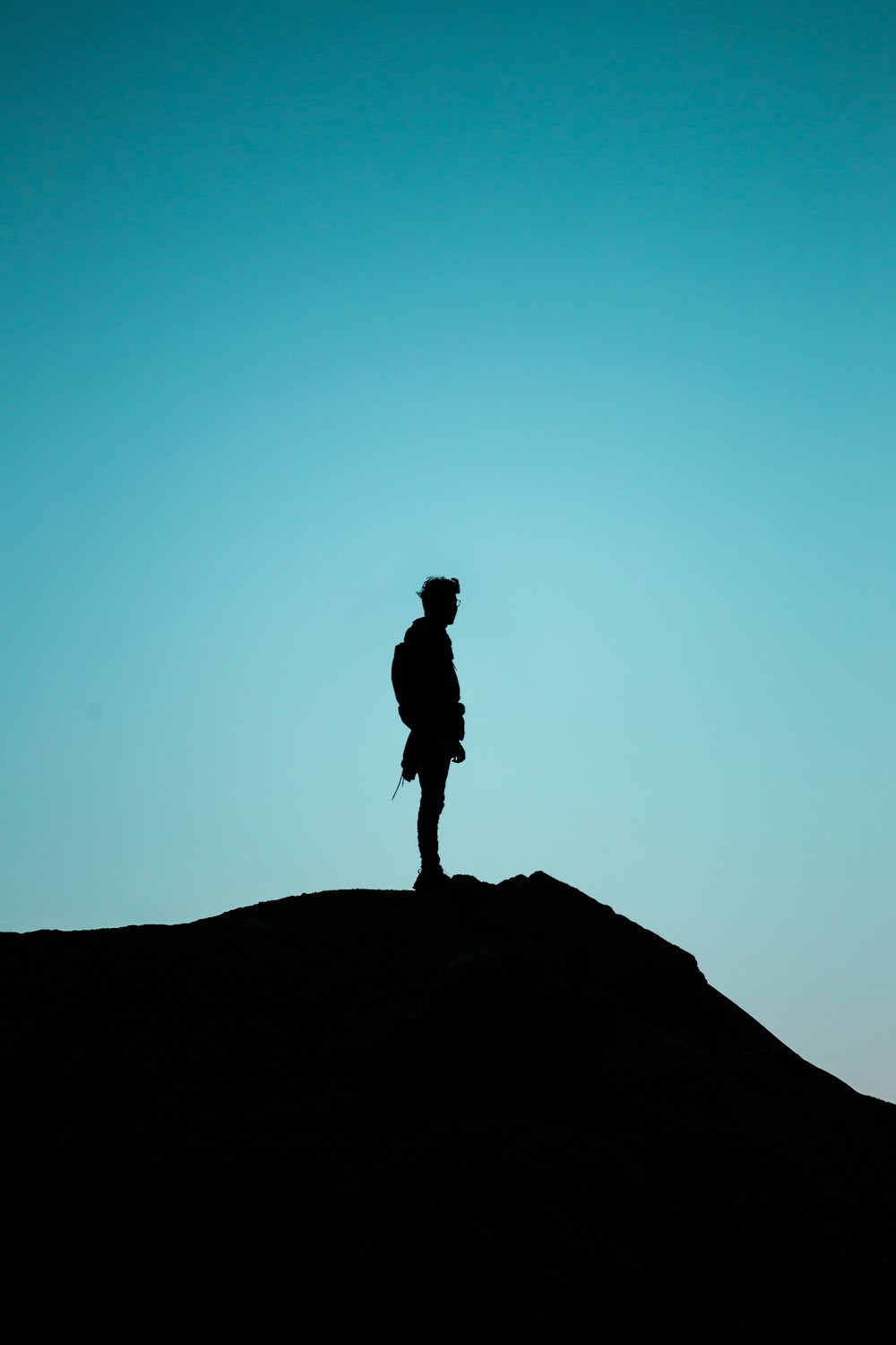 silhouette d’homme debout sur la formation rocheuse pendant la journée