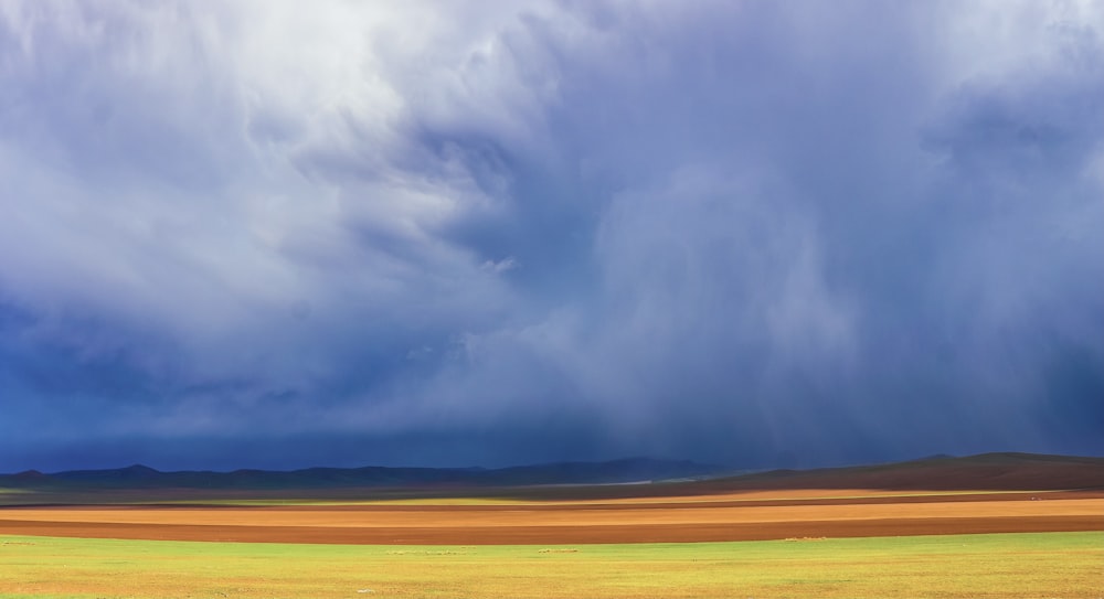 brown field under white clouds