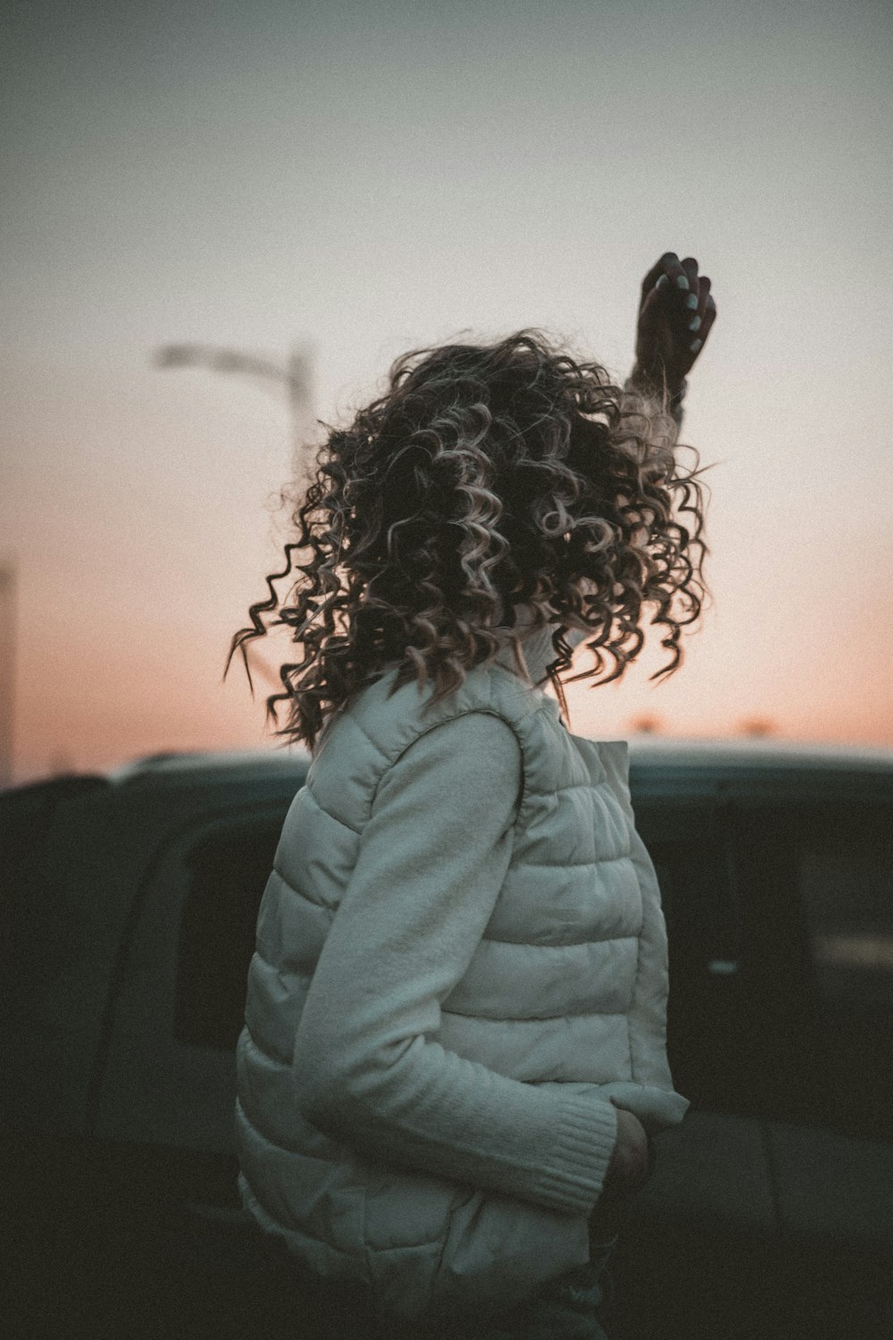 woman in blue jacket standing near black car