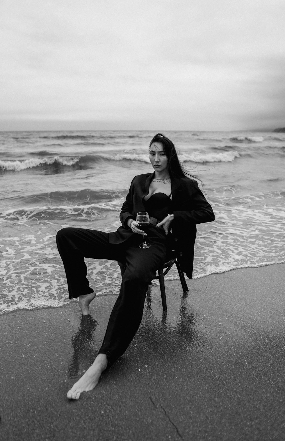 woman in black jacket and pants sitting on black chair on beach