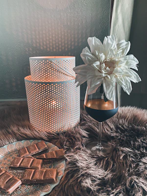 A serene setting with a single chocolate square resting on a plate next to a softly glowing candle.