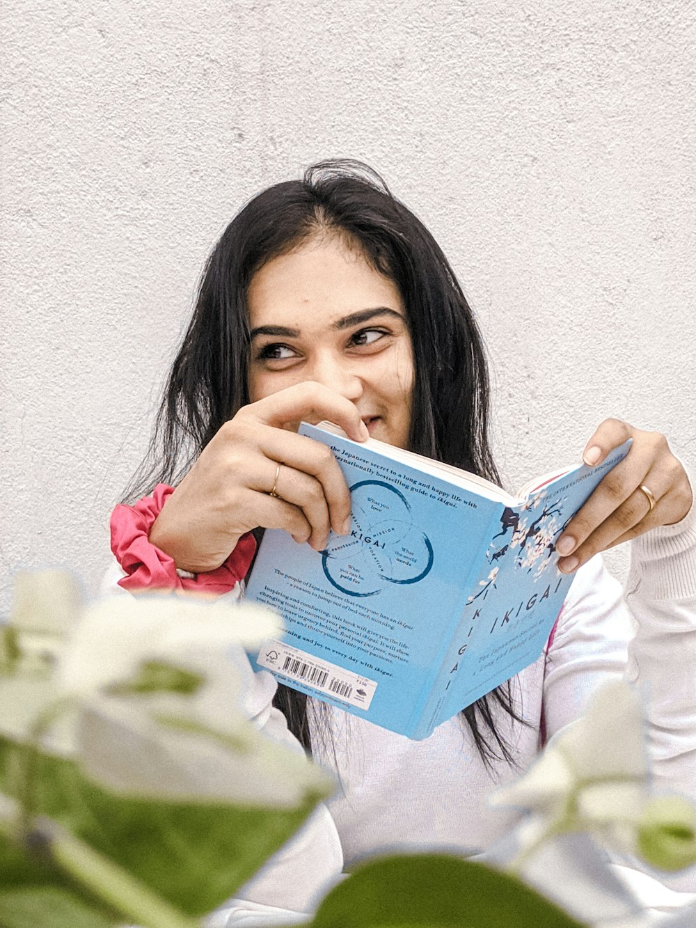 woman in white long sleeve shirt holding blue book