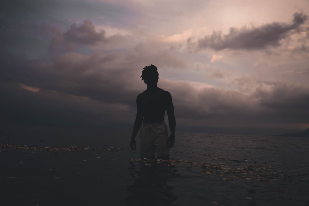 silhouette of woman standing on beach during sunset