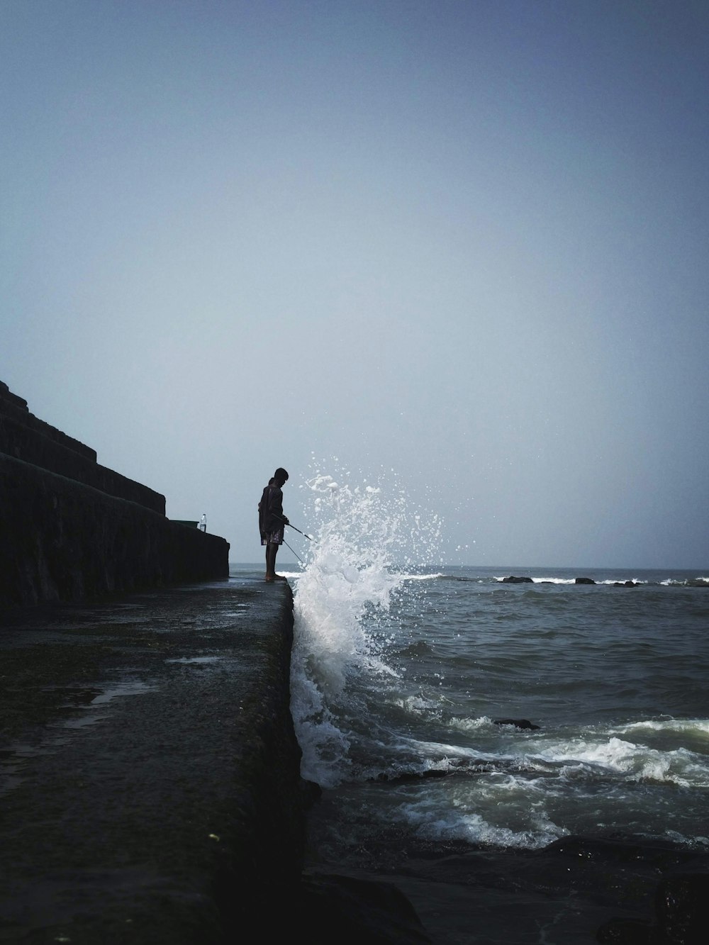 silhouette of person standing on rock near sea during daytime