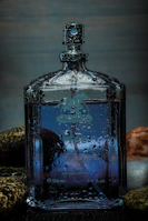 Close-up of a glass bottle with aroma drops surrounded by soft grey stones.