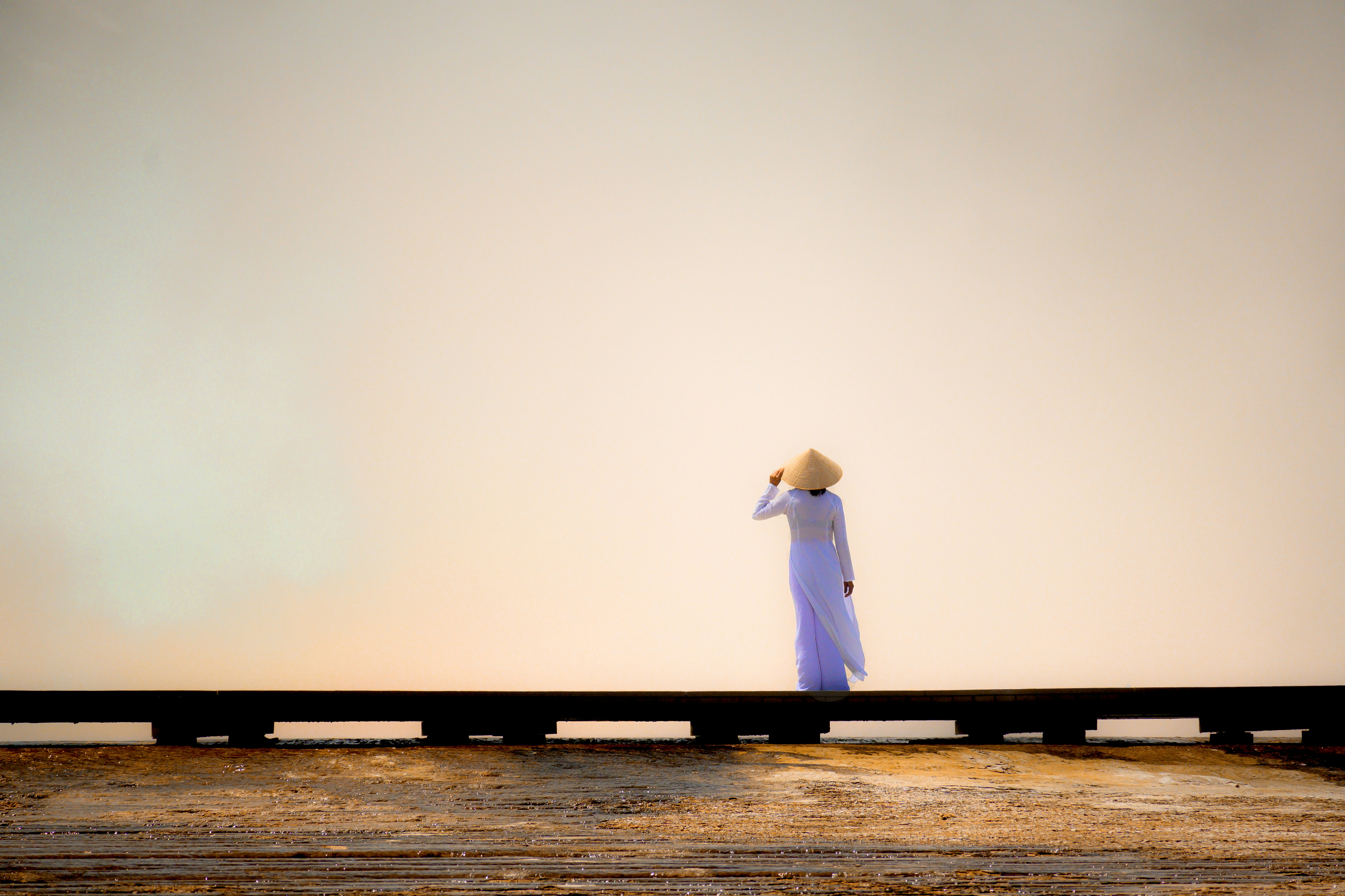 woman in white dress standing on brown wooden dock during daytime