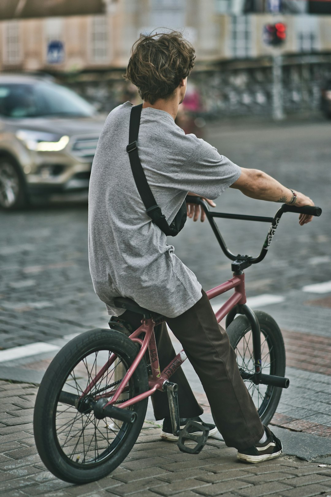 man in gray shirt riding red bicycle on road during daytime