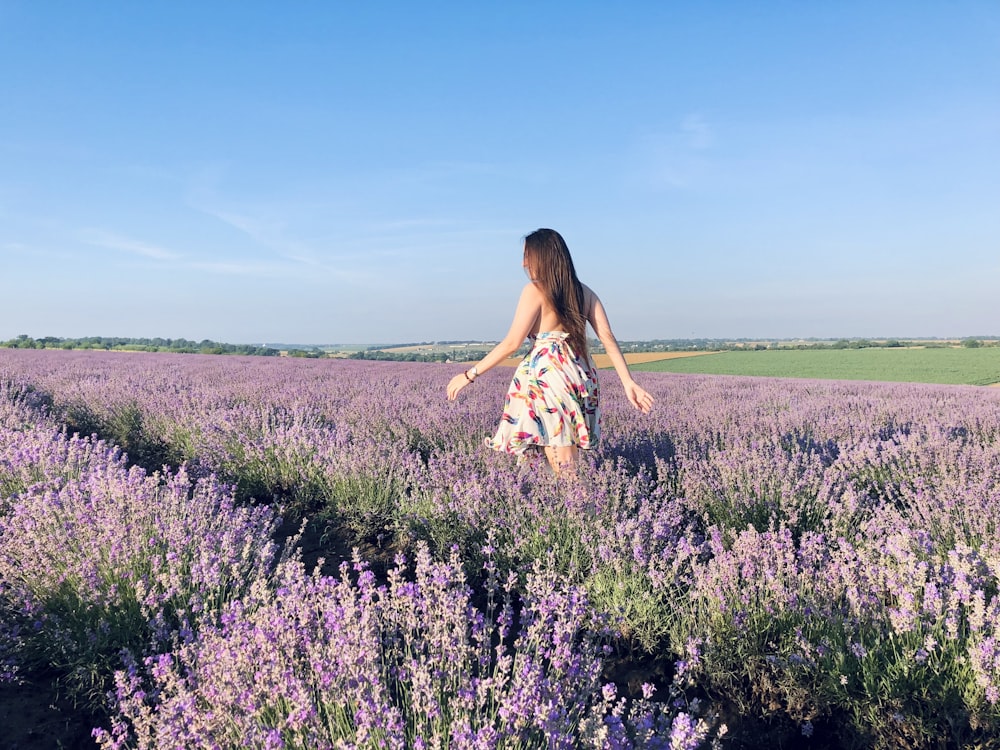 woman in white and blue floral dress standing on purple flower field during daytime