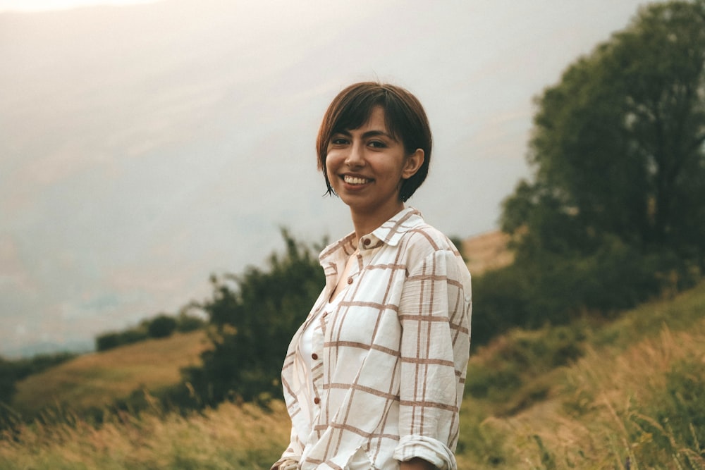 woman in white and brown plaid dress shirt standing on green grass field during daytime