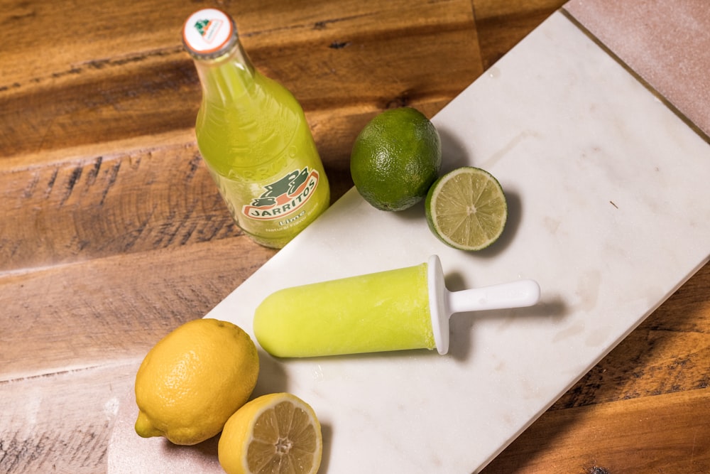 lemon and green bottle on white table