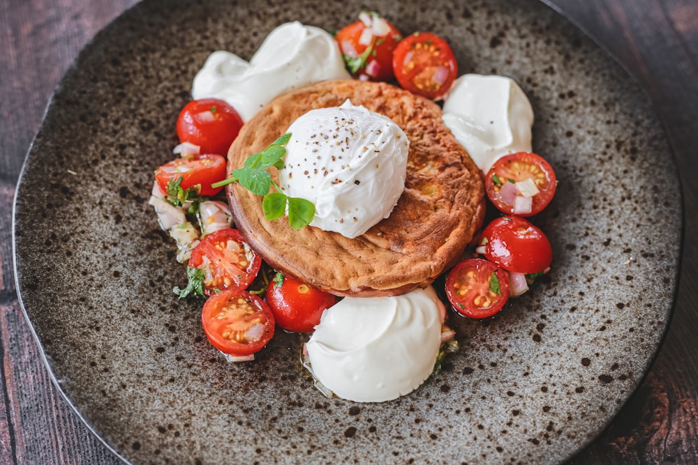 Tomate tranchée et crème blanche sur assiette en céramique noire