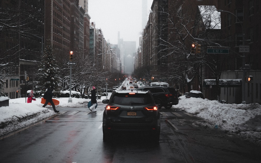 black car on road covered with snow during daytime