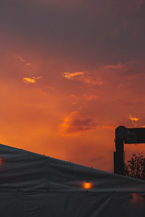 Sunset over the rustic festival grounds with orange and teal tents glowing warmly.