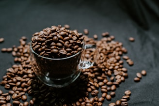 A steaming cup of rich, dark coffee surrounded by coffee beans.