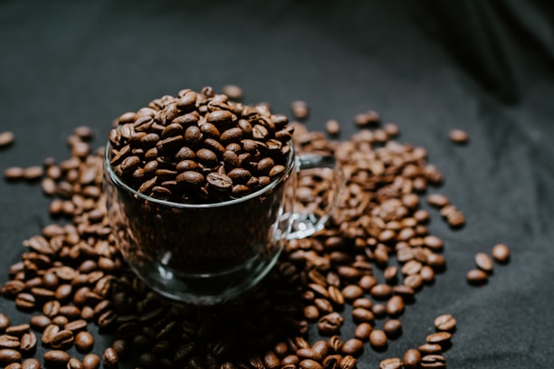 A steaming cup of rich, dark coffee surrounded by coffee beans.