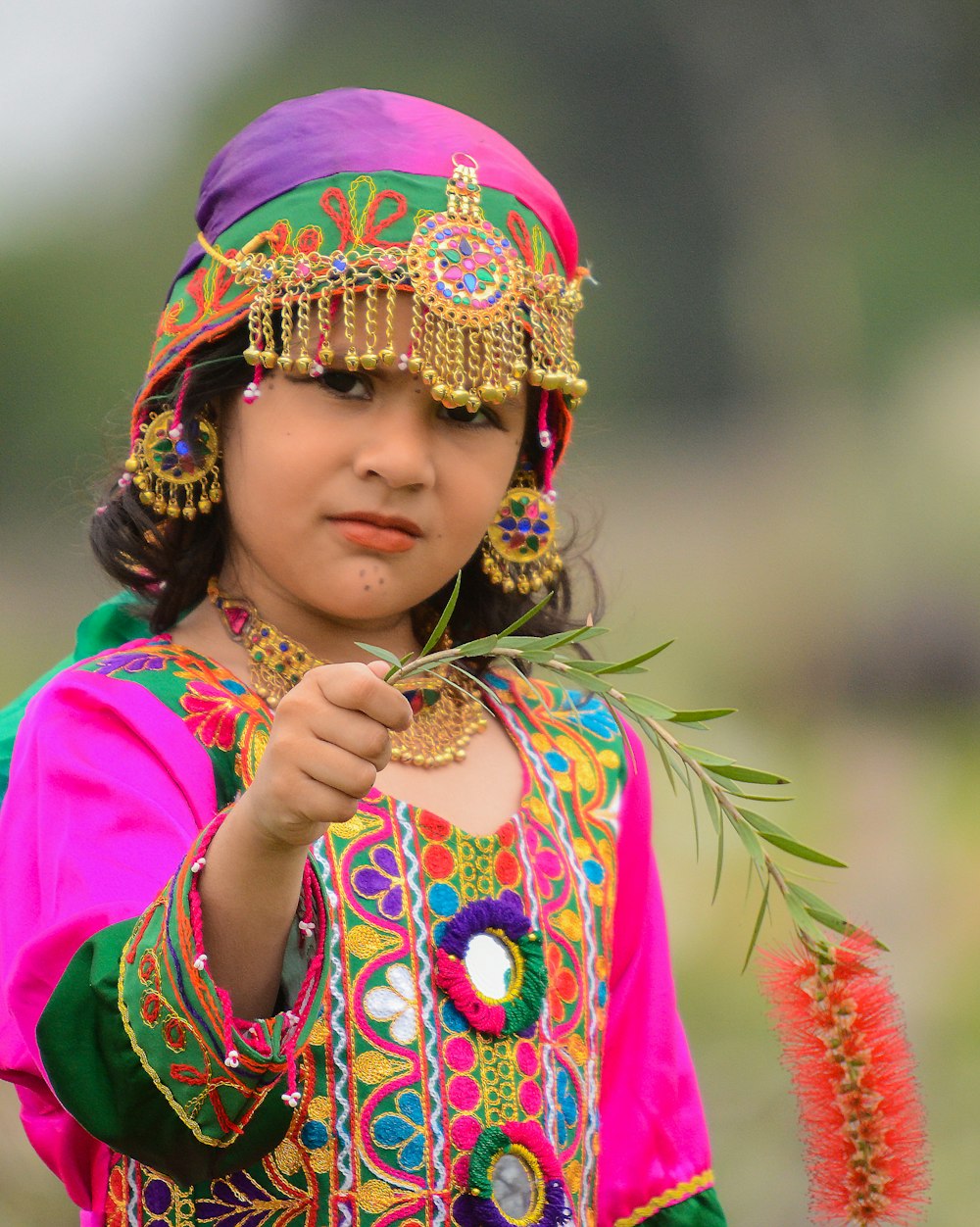 girl in pink and yellow floral dress wearing blue and pink headdress