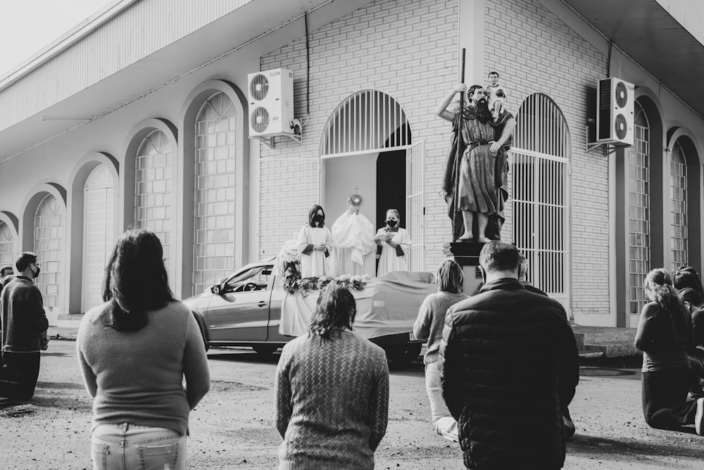 grayscale photo of people standing near car