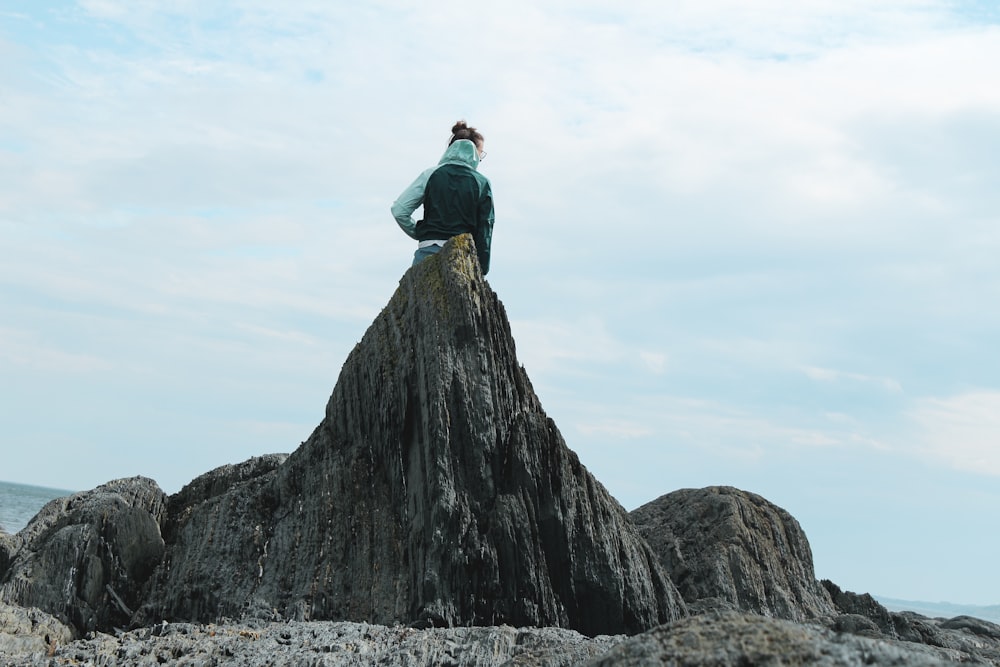昼間、岩の上に座る黒いジャケットの男
