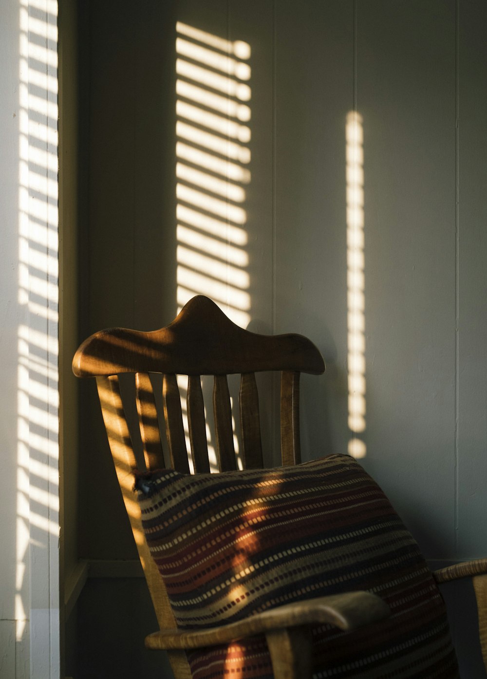 brown wooden armchair beside white window blinds