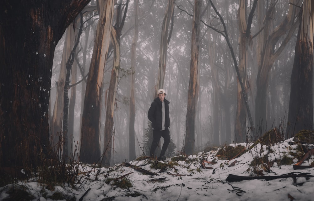 man in black jacket standing on snow covered ground