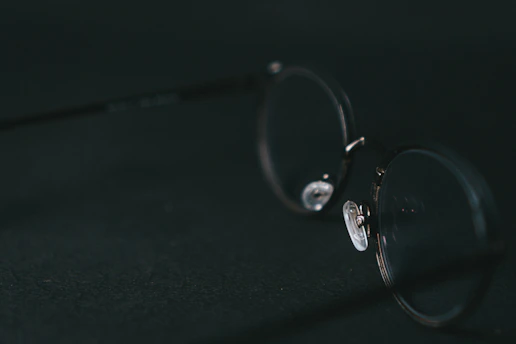 Close-up of elegant premium eyeglasses resting on a minimalist white surface with soft natural lighting.