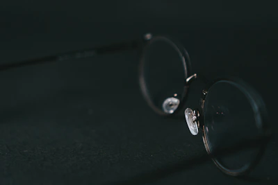 Close-up of premium eyeglasses resting on a minimalist white surface with soft lighting.