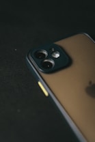 A close-up view of a smartphone with a focus on its camera module, featuring multiple lenses. The image is taken at an angle, highlighting the sleek design and glossy surface of the device against a dark background.