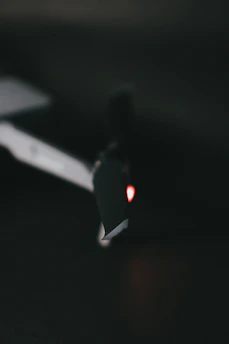 Close-up of a drone technician carefully inspecting rotor blades under soft blue lighting.
