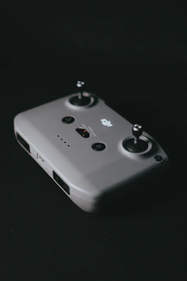 Close-up of a sleek drone controller with glowing buttons against a baby blue background.