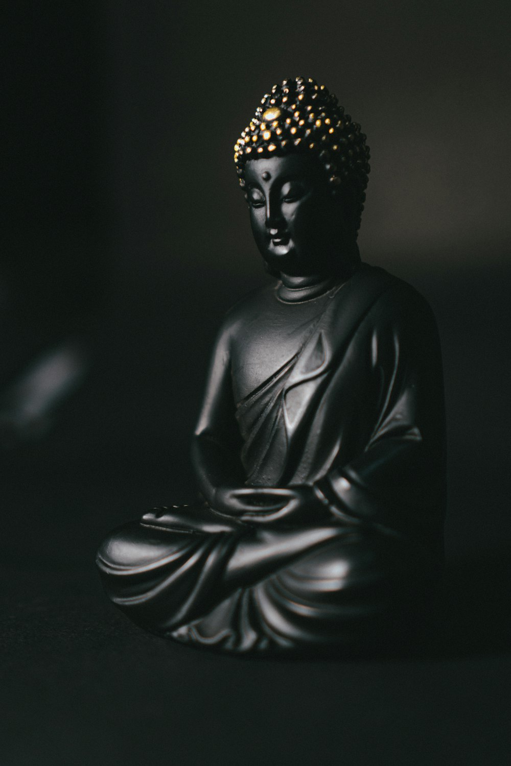 Statua nera del Buddha Gautama su superficie nera