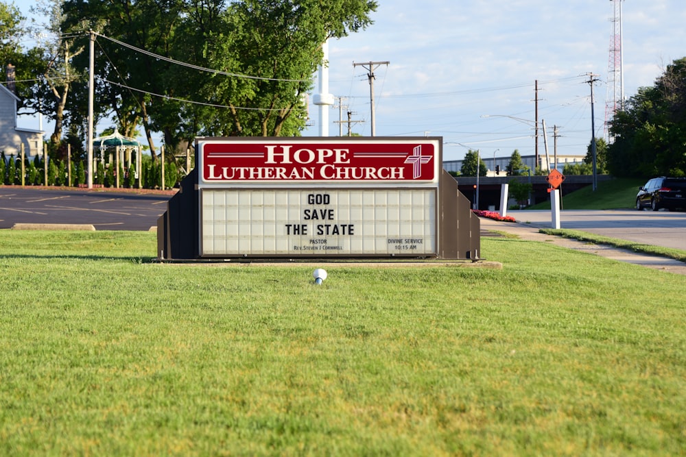 a church sign in a grassy area with a car in the background