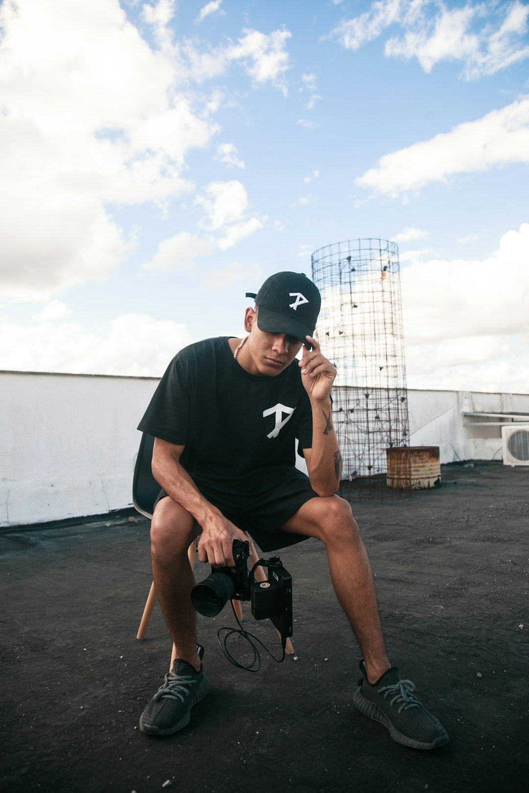man in black crew neck t-shirt and black nike cap sitting on brown wooden chair