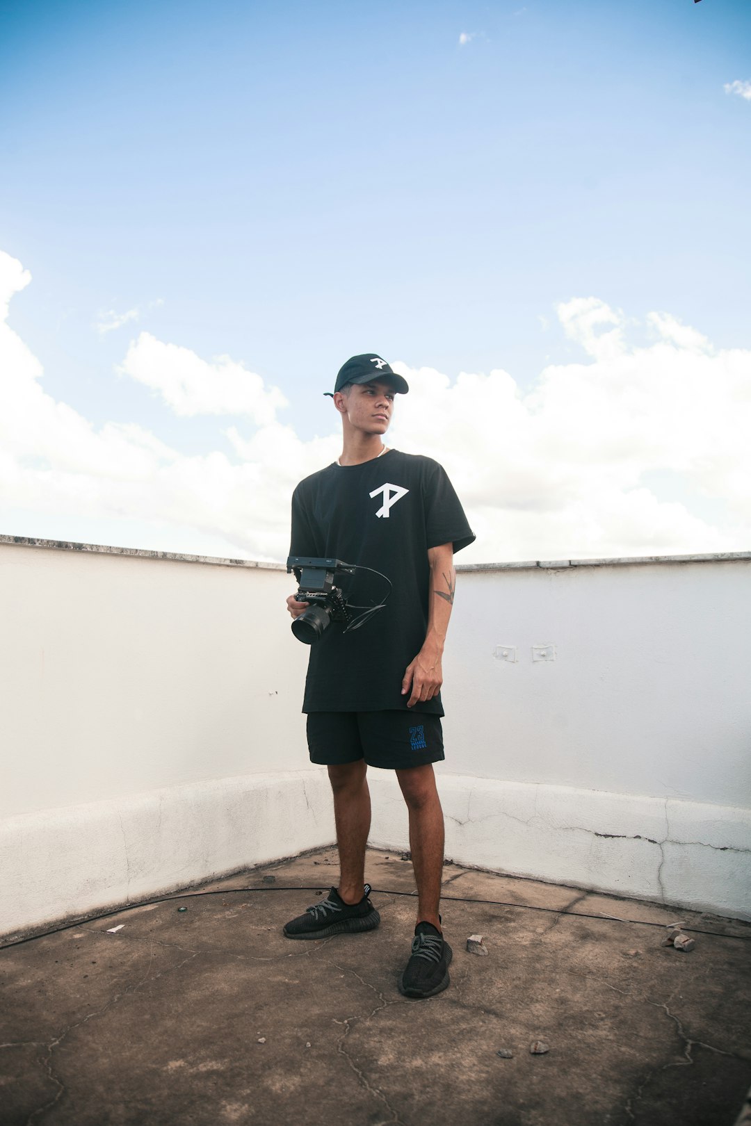 man in black crew neck t-shirt and black shorts standing on brown wooden dock during