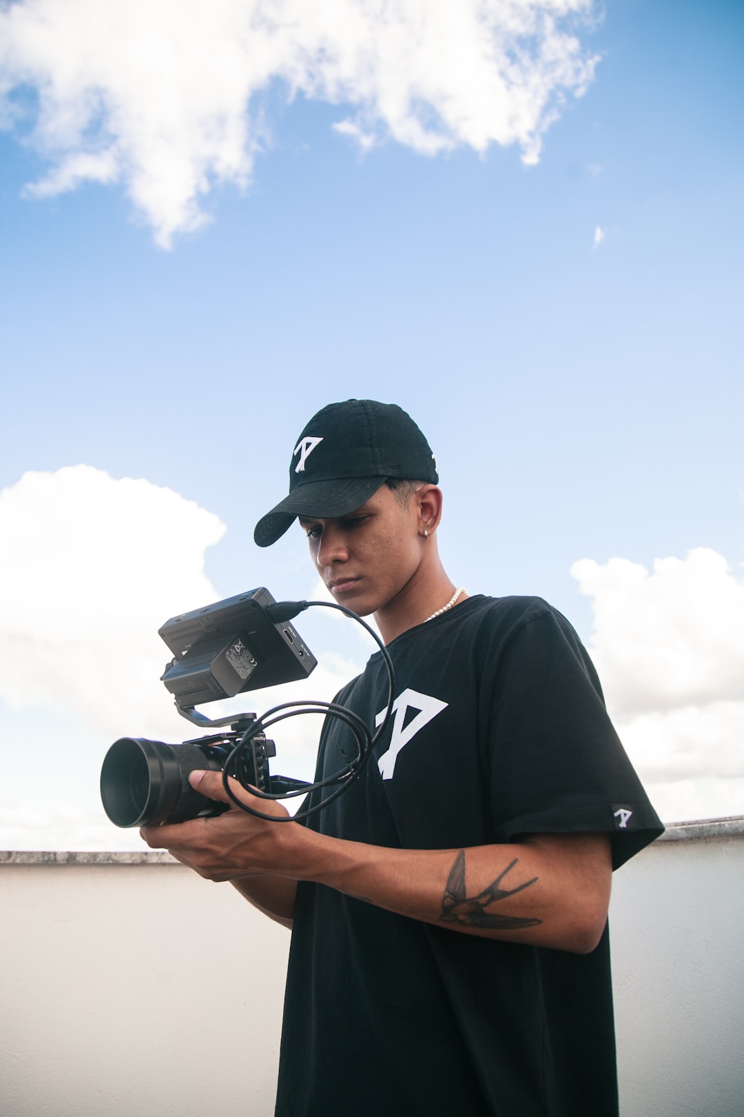 man in black crew neck t-shirt holding black dslr camera during daytime