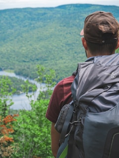 A friendly guide helping travelers with backpacks against a backdrop of lush mountains.