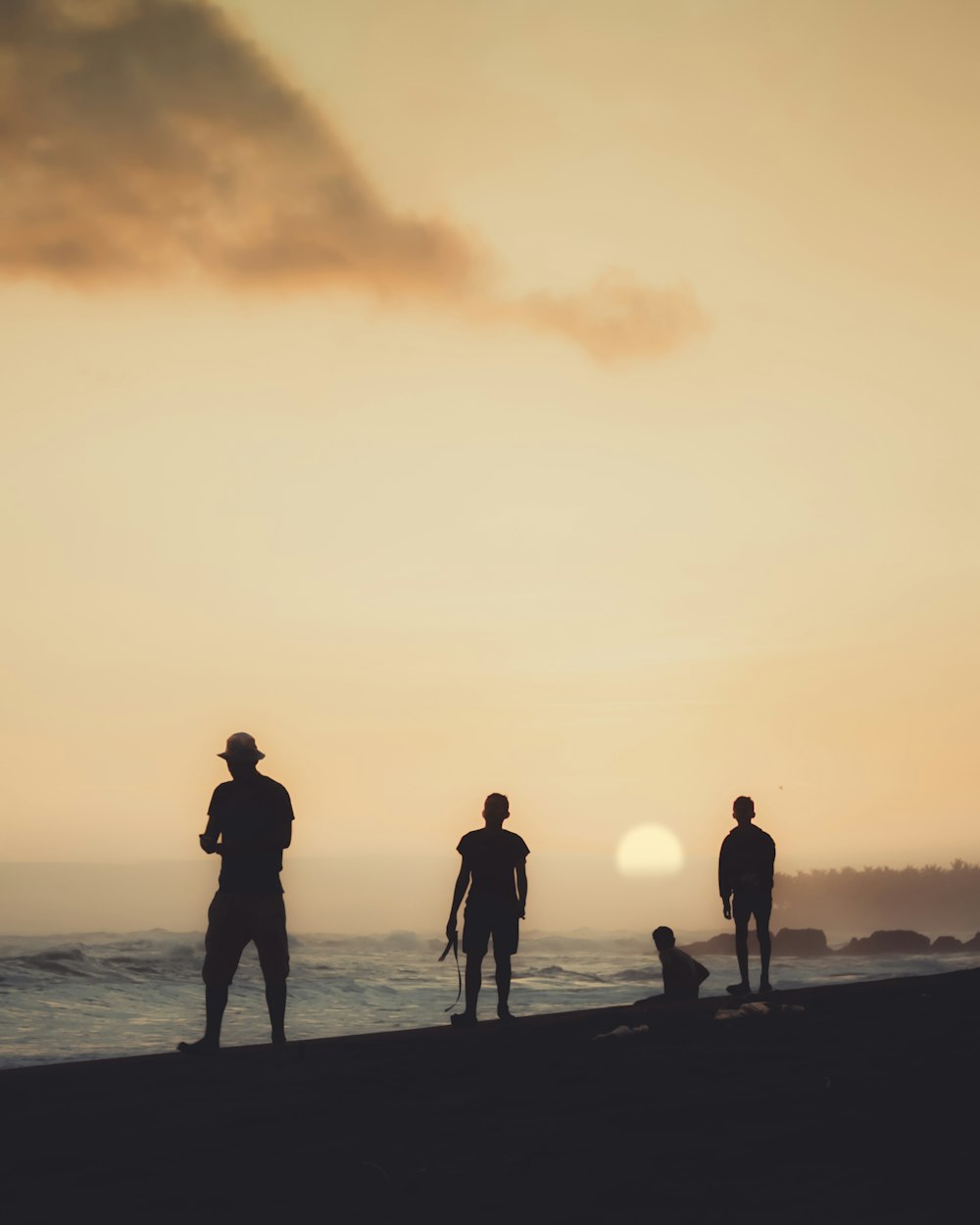 silhouette of 3 people walking on beach during sunset