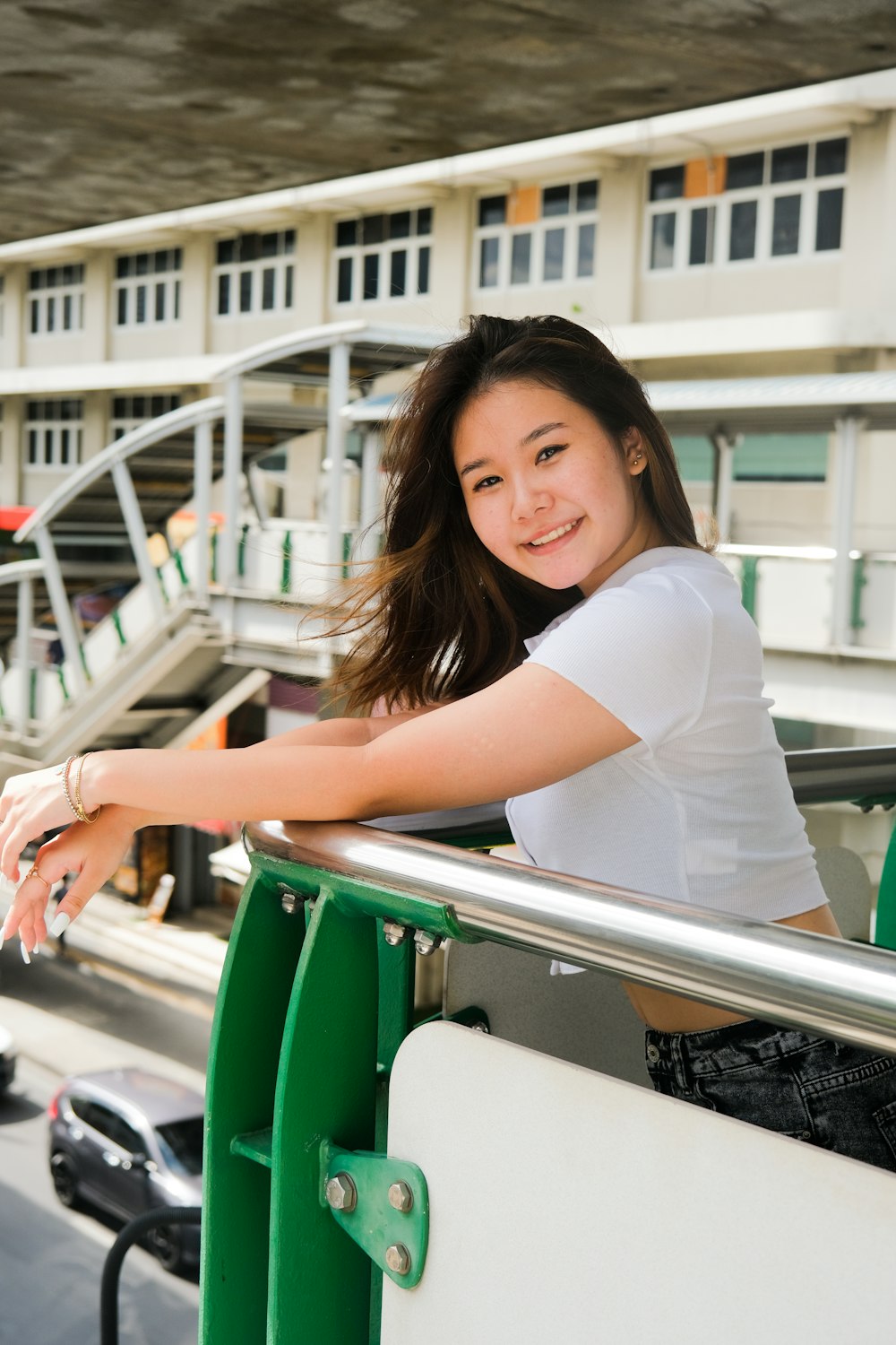 woman in white t-shirt leaning on green metal railings