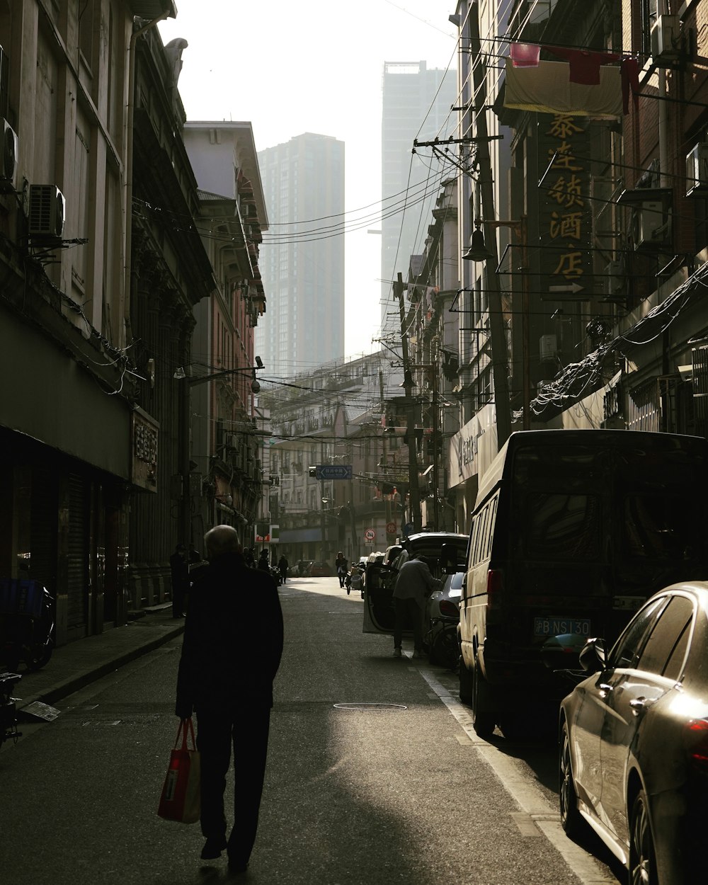 man in black coat walking on sidewalk during daytime