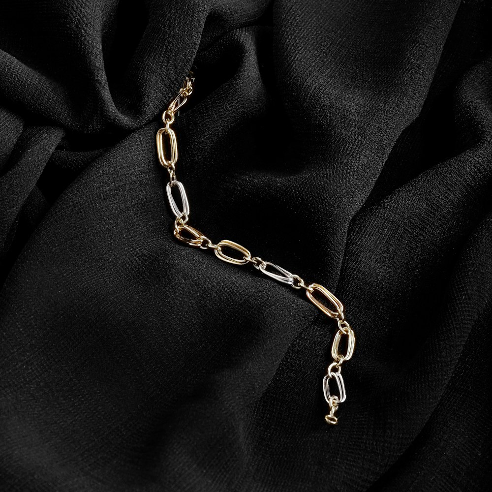 gold chain necklace on black textile