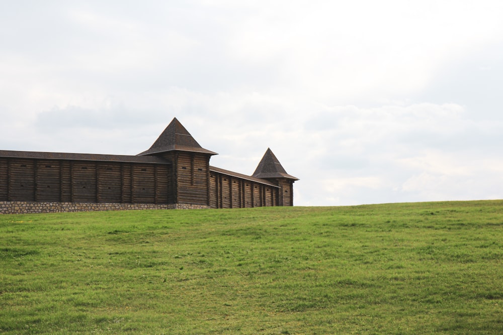 Edificio de ladrillo marrón en campo de hierba verde bajo cielo blanco durante el día