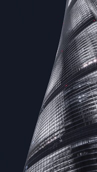 A sleek black and gold luxury apartment building illuminated against a twilight city skyline.