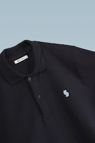Close-up of a sleek polo shirt with subtle stitching, resting on a minimalist concrete background.