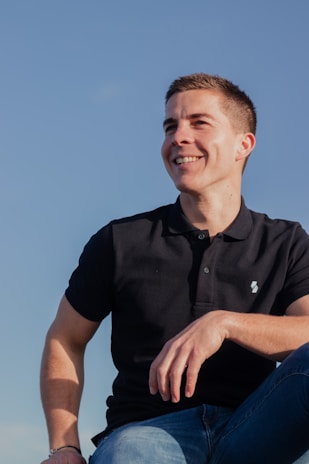 A smiling young adult walking outdoors, feeling light and hopeful under a clear sky.