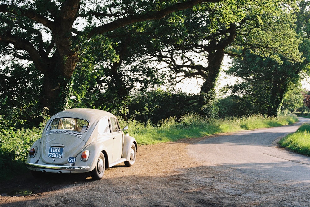 white volkswagen beetle parked on dirt road during daytime